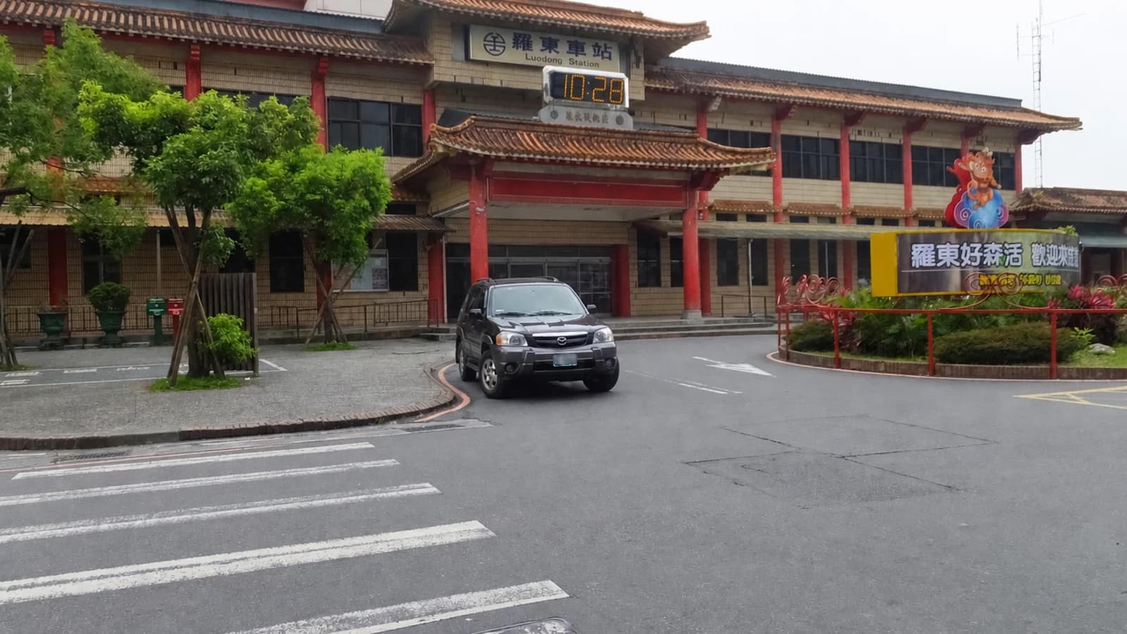 Harapan ng Luodong Station at kalsada sa tapat nito, na kita ang pangalan ng estasyon, sasakyan at mga puno