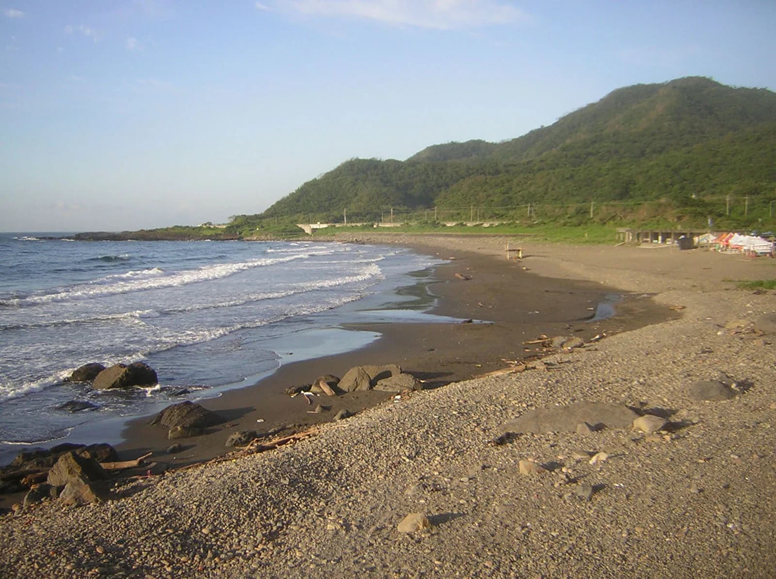 Geschwungene dunkle Sandküste, Felsen und Meer an der Daxi Honeymoon Bay